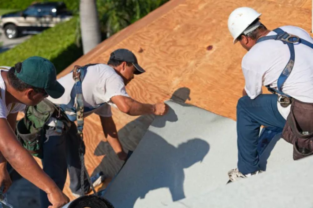 A team of four men working on a roof with a ladder, representing a roofing construction service in San Diego, CA.
