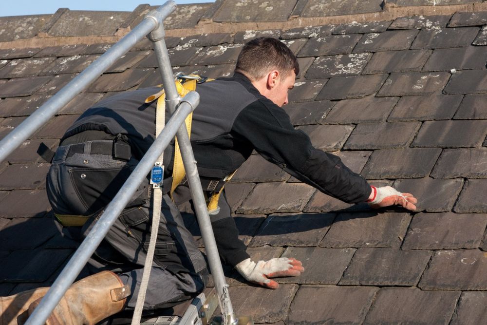 A man is seen on a ladder, diligently repairing a roof, highlighting our roof repair service in San Diego, CA.