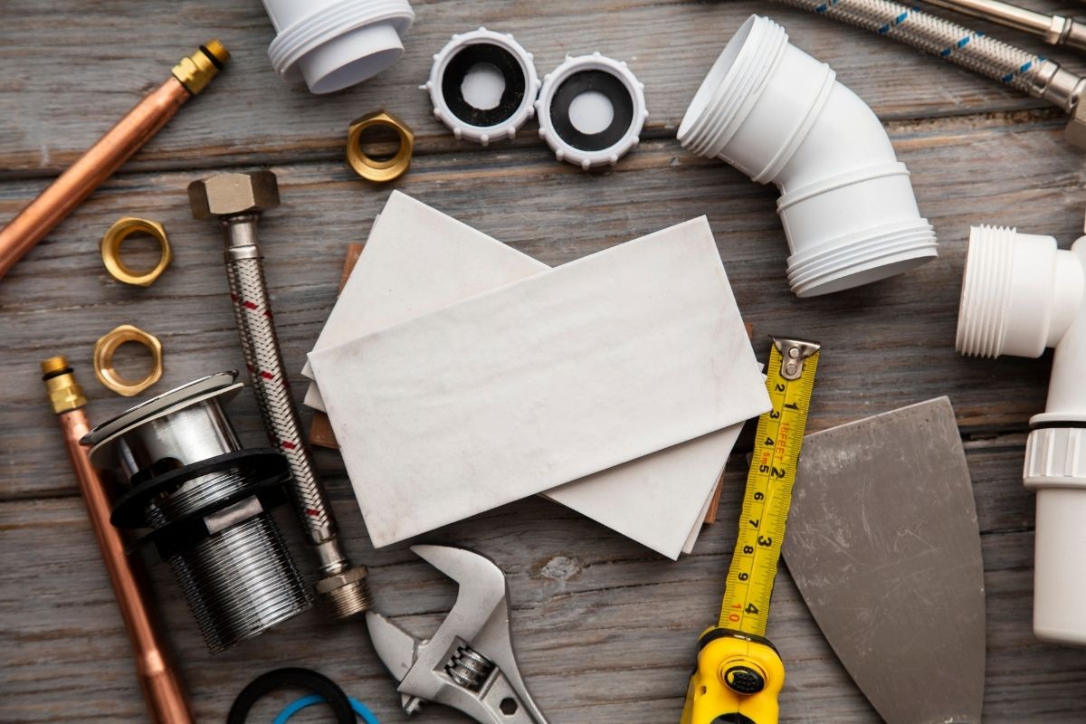 A wooden table filled with plumbing tools and supplies, showcasing wrenches, fittings, and various plumbing materials.